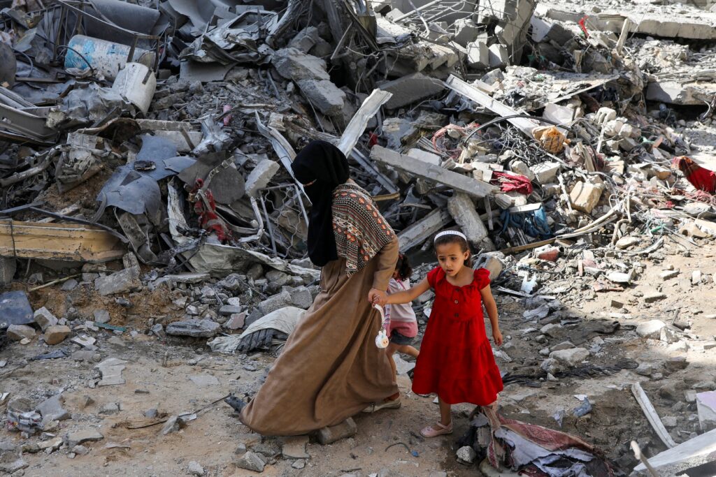 A woman and child walk among debris in the Nuseirat refugee camp in the central Gaza Strip, June 9, 2024, aftermath of Israeli strikes at the area, where Israeli hostages were rescued, amid the Israel-Hamas conflict.