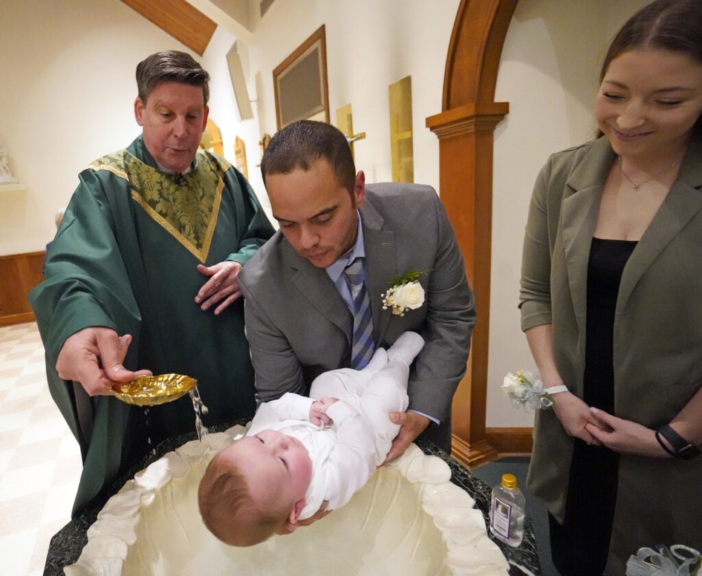 Julio Prendergast holds his five-month-old son, Gabriel James, as he is baptized by Monsignor Frank Schneider Nov. 12, 2022, at St. John the Baptist Church in Wading River, N.Y. Looking on is the baby's mother, Christina Prendergast.