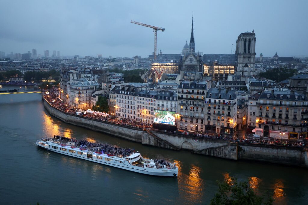 An athlete boat on the Seine River passes in front of the Notre Dame Cathedral on July 26, 2024, during the opening ceremony of the Olympic Games in Paris.