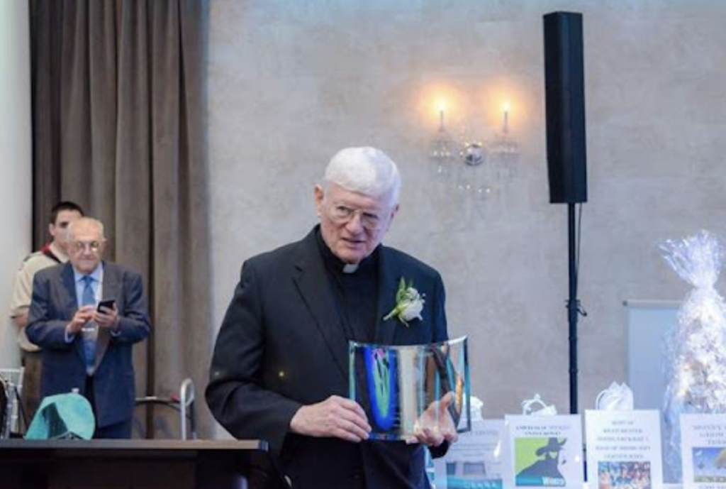 Monsignor Hugh McManus accepts a "treasure" award at the Annunciation- Our Lady of Fatima Church Faith & Treasures Dinner Dance in 2017.