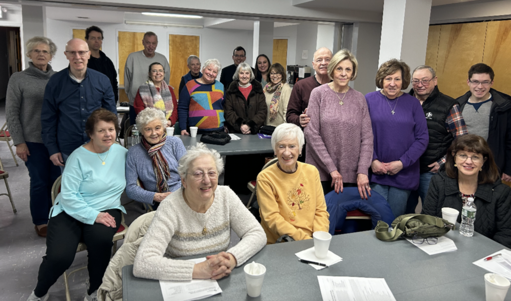 Claire Smith (far left in gray), parish director of Adult Faith Formation, stands with a St. Clare Church of Staten Island group photo taken during a 2024 Lenten program on Eucharistic Revival that the parish Adult Faith Formation Committee sponsored.