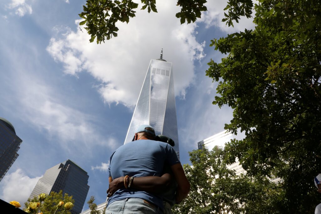 People in New York City embrace September 11, 2021, as they visit the 9/11 Memorial on the 20th anniversary of the September 11 attacks.