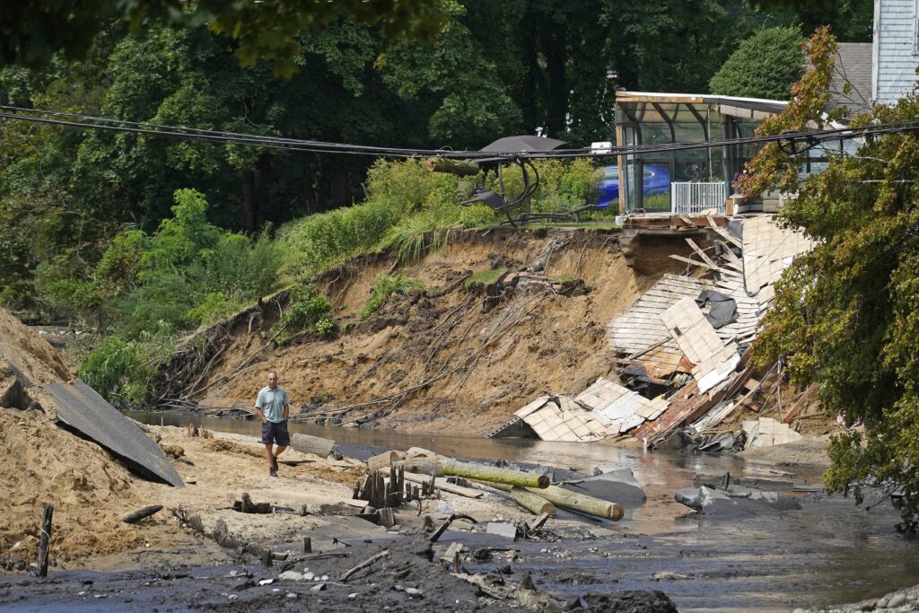 A man walks on the dirt and sand foundation of Harbor Road in Stony Brook on August 19, 2024, after it collapsed earlier in the day when torrential rain caused a dam beneath the road to burst.