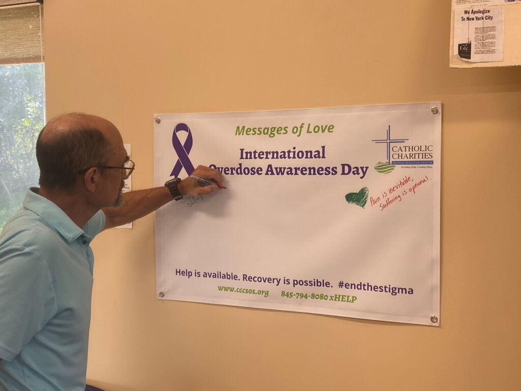 A visitor signs a banner at Catholic Charities of Orange, Sullivan, and Ulster's 2023 International Overdose Awareness Day event.