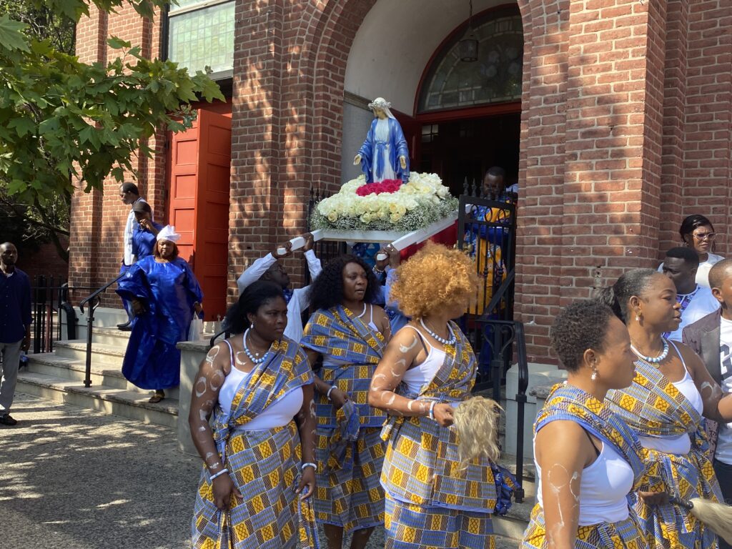 Parishioners in traditional garb of St. Joseph of the Holy Family in West Harlem line up to begin the annual Assumption procession, Sunday, August 18, 2025.