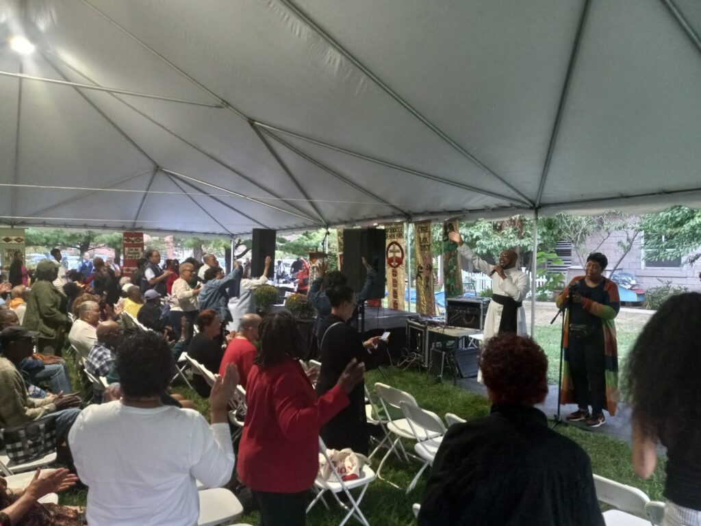 Father Kareem Smith and others lead the people in praise and worship songs during the Old-Fashioned Tent Revival at St. Michael the Archangel Church in the Bronx, Tuesday, September 17, 2024. Photo by Armando Machado/The Good Newsroom