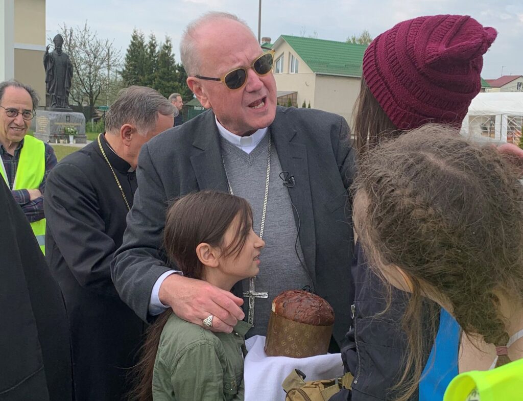 New York Cardinal Timothy M. Dolan, chairman of the Catholic Near East Welfare Association, embraces a girl who greeted him with bread and salt, a traditional way to greet and honor guests in Slavic cultures, during a visit to Lviv, Ukraine, May 2, 2022.