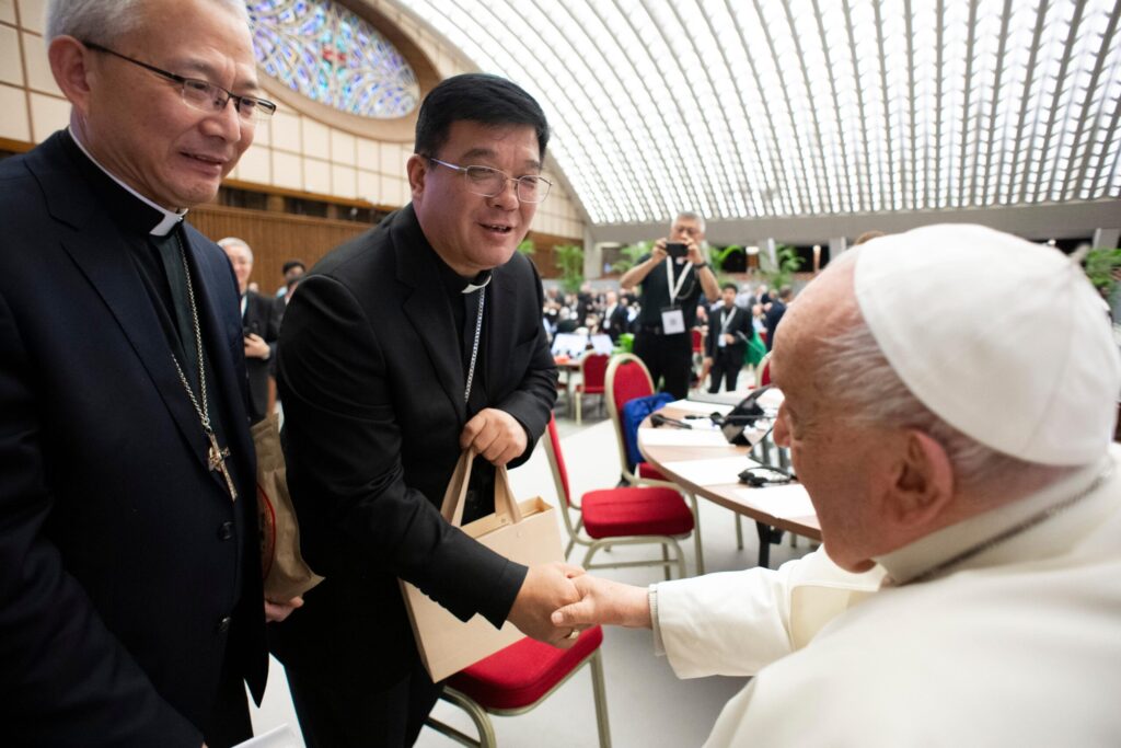 Bishop Joseph Yang Yongqiang of Hangzhou, China, shakes hands with Pope Francis while Bishop Vincent Zhan Silu of Funing-Mindong, the other member of the Synod of Bishops from mainland China, looks on in the Paul VI Audience Hall at the Vatican October 8, 2024.