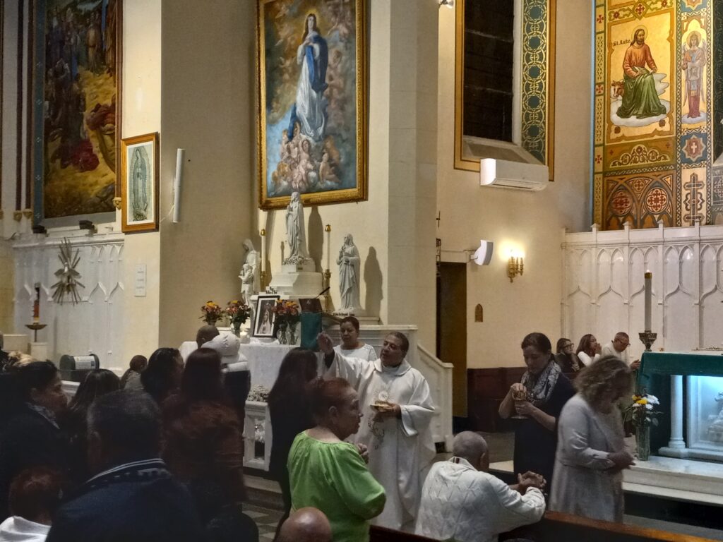 Father Ambiorix Rodriguez (center) during Holy Communion at the Hispanic Heritage Month Mass, St. Elizabeth Church in Manhattan's Washington Heights, Friday, October 11, 2024.