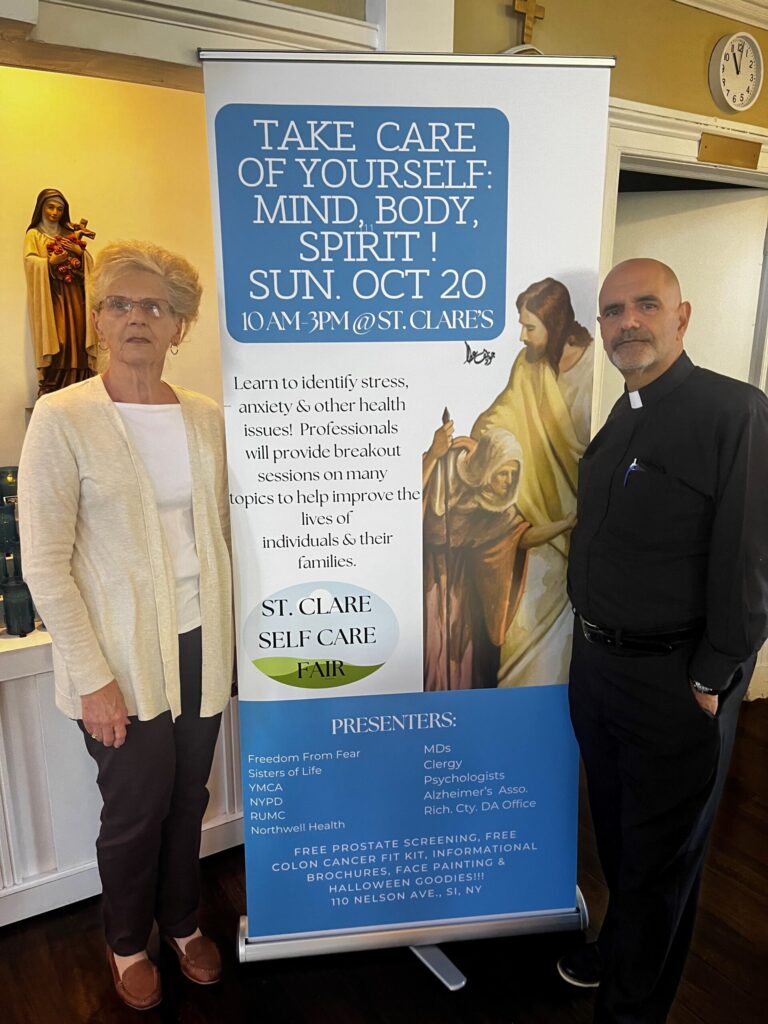 Claire Smith, director of Adult Faith Formation (left), and Father Arthur Mastrolia, pastor, with an informational poster about the October 20 Self-Care Fair at St. Clare Church on Staten Island.