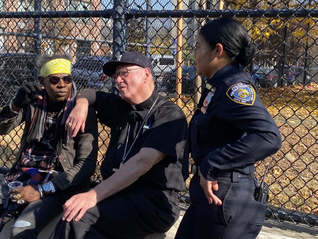 Cardinal Timothy Dolan (center) chats with a local resident of the Hunts Point section of the Bronx (left) and an officer from the New York Police Department’s 41st Precinct during a weekly food distribution by LAMP Catholic Ministries, October 30, 2024.