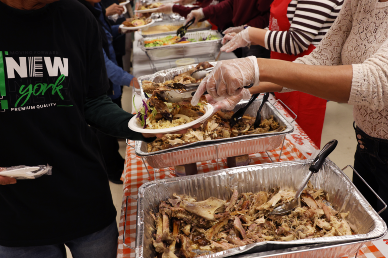 Turkey is added onto a heaping plate at the end of the line at Alianza’s Thanksgiving meal in Harlem.