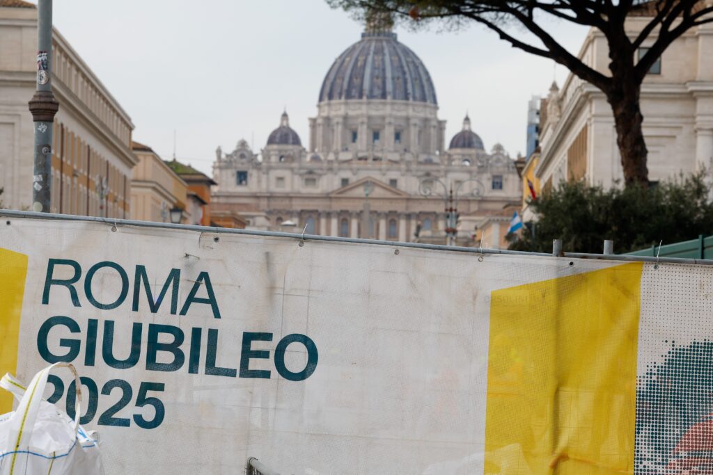 The dome of St. Peter's Basilica is seen over a cloth barricade reading "Rome Jubilee 2025" that surrounds a construction site at the beginning of the broad boulevard leading to St. Peter's Square December 4, 2024.