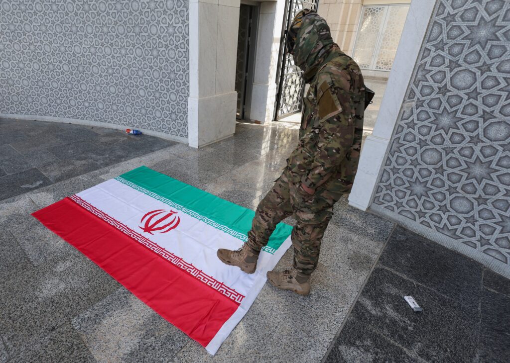 A rebel fighter walks above the Iranian flag at the entry hall in Presidential Palace known as Qasr al-Shaab "People's Palace," after rebels seized the capital and ousted Syria's Bashar Assad, in Damascus, Syria, December 10, 2024.