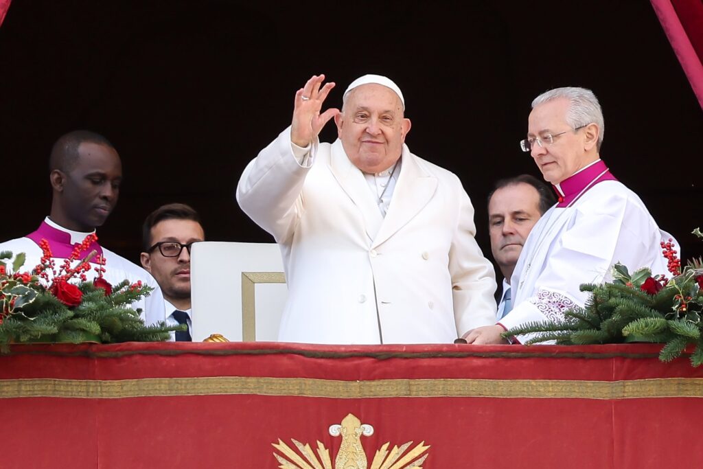 Pope Francis waves to visitors gathered in St. Peter's Square after delivering his Christmas message and blessing "urbi et orbi" (to the city and the world) from the central balcony of St. Peter's Basilica at the Vatican on December 25, 2024.