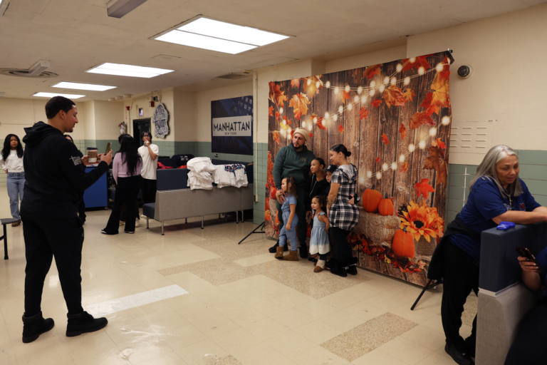 A family gets their photo taken in front of the fall background set up for holiday cards.