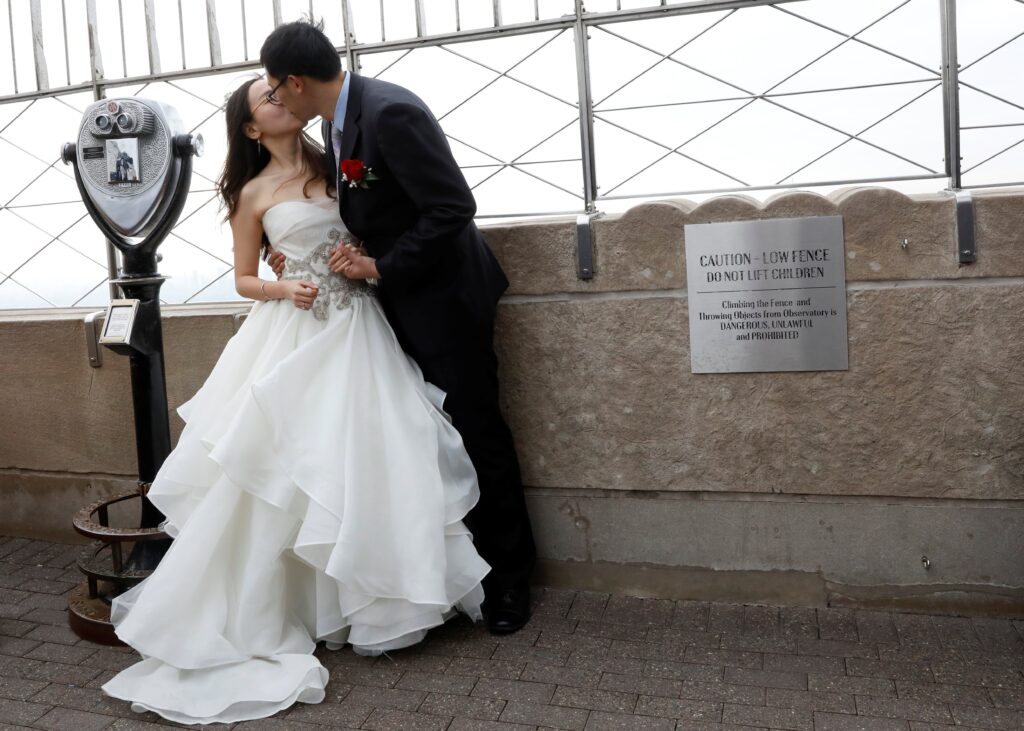 An Wang and Wei Cui kiss at the top of the Empire State Building in New York after their Valentine's Day wedding, February 14, 2018.