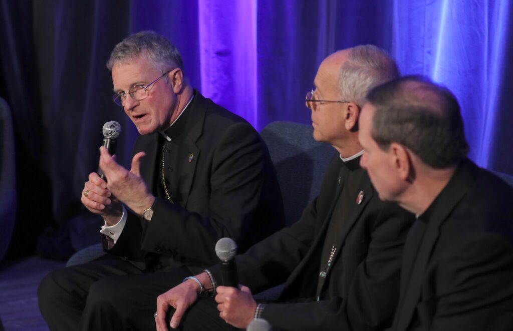 Archbishop Timothy P. Broglio of the U.S. Archdiocese for the Military Services, president of the U.S. Conference of Catholic Bishops (left), speaks during a news conference at a November 12, 2024, session of the fall general assembly of the USCCB in Baltimore.