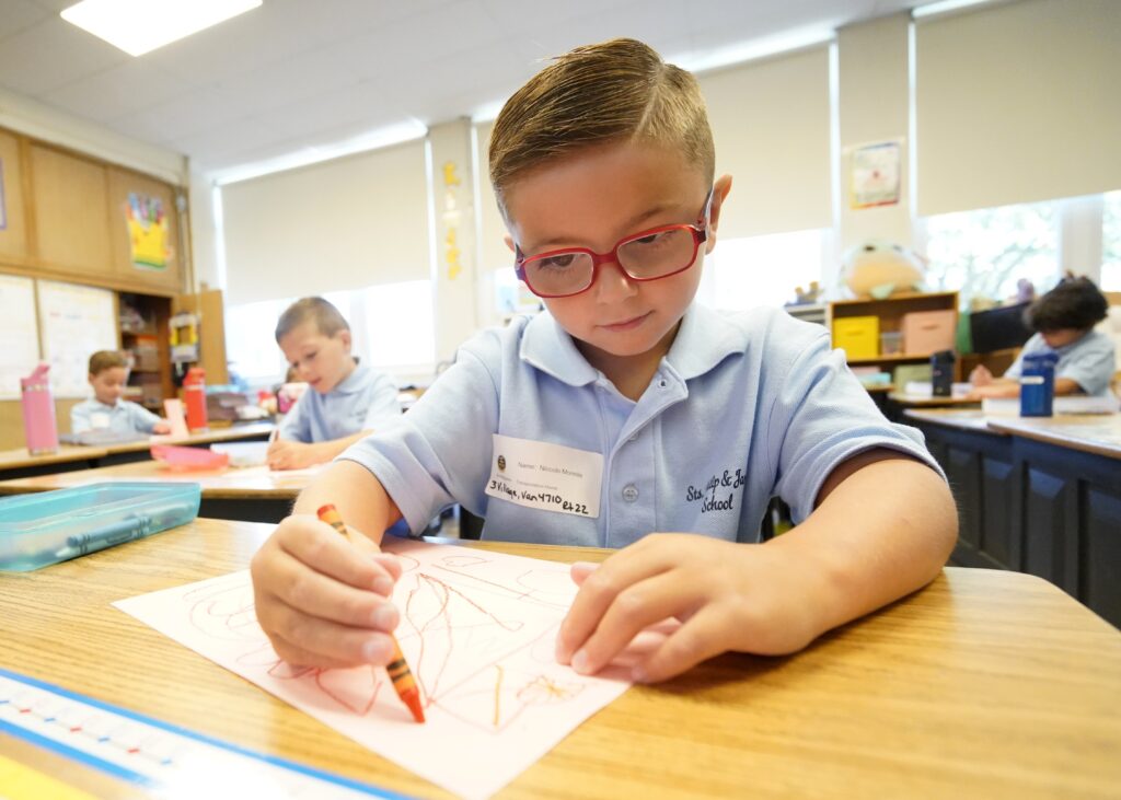 Kindergartener Niccolo Mormile uses a crayon as he works on an assignment on the first day of classes at Sts. Philip and James School in St. James, September 4, 2024.