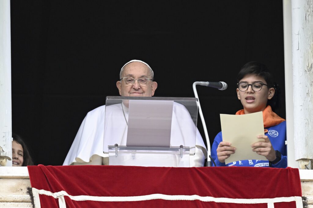 Pope Francis stands next to a young boy, representing Rome's Catholic Action, who is addressing the crowd with an appeal for peace after the recitation of the Angelus prayer in St. Peter's Square at the Vatican on January 26, 2025.