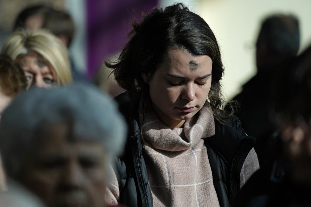 A worshipper returns to her pew after receiving Communion during an Ash Wednesday Mass at Holy Cross Church in Nesconset on February 22, 2023.