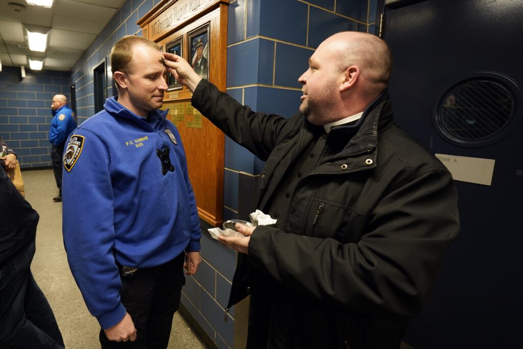 Father Sean Suckiel, pastor of Holy Family Church in Fresh Meadows, imposes ashes on Police Officer Tim Gorman of the New York Police Department at the 107th Precinct in Fresh Meadows on February 14, 2024.