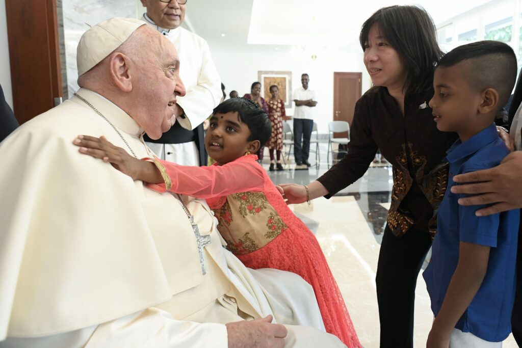 Pope Francis receives a hug from a child as he meets migrants, refugees, orphans, the elderly and the sick at the apostolic nunciature in Jakarta, Indonesia, September 3, 2024.