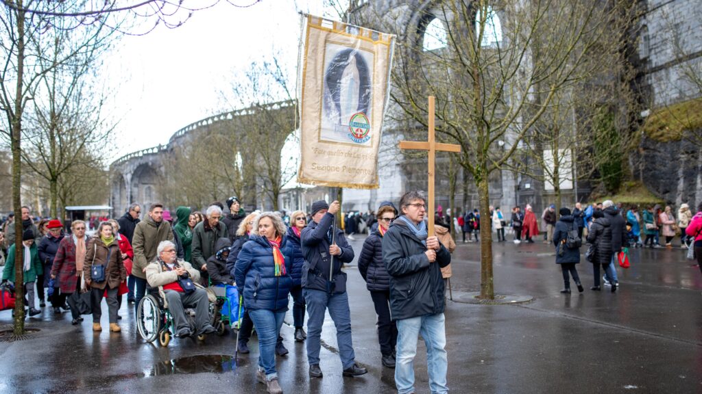 People walk in a procession near the grotto of the apparitions February 11, 2024, at the shrine of Our Lady of Lourdes in southern France.