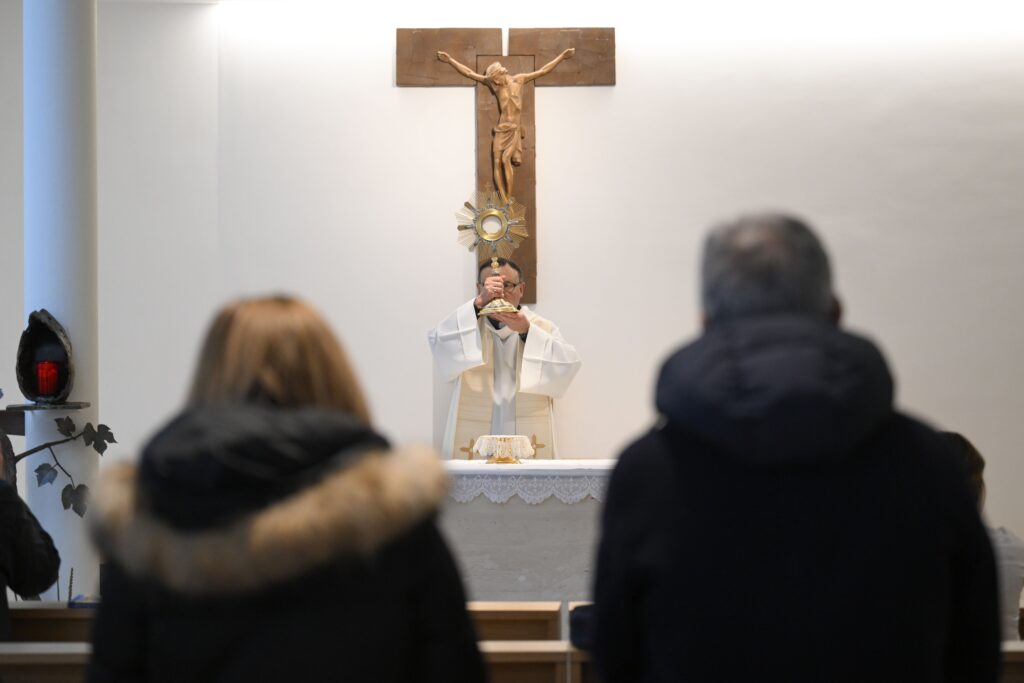 Un sacerdote dirige la Adoración Eucarística mientras profesionales sanitarios, pacientes y familiares del Gemelli de Roma rezan por el Papa Francisco el 24 de febrero de 2025, en la capilla del hospital.