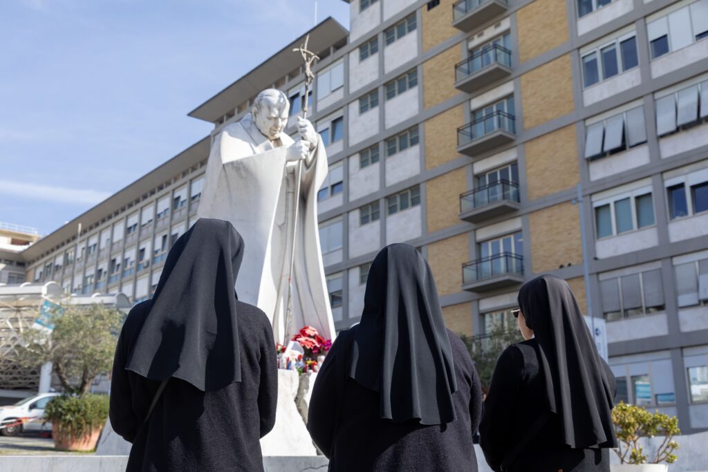 Religiosas rezan en el patio frente a la estatua de San Juan Pablo II en el hospital Gemelli de Roma el 23 de febrero de 2025, donde el Papa Francisco está siendo tratado de una neumonía doble.