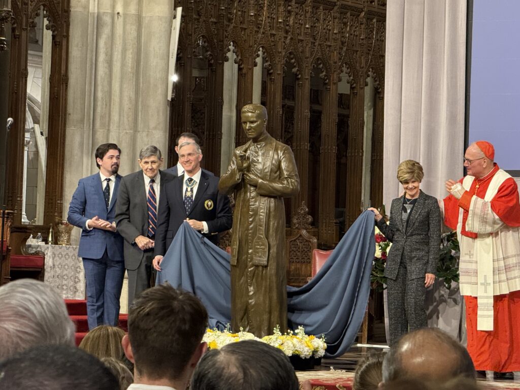 Cardinal Timothy Dolan (right, in red), Supreme Knight Patrick Kelly (left of statue), and members of the McGivney family unveil a bronze statue of Blessed Michael McGivney donated by the Knights of Columbus to St. Patrick's Cathedral, on Saturday, February 22, 2025.