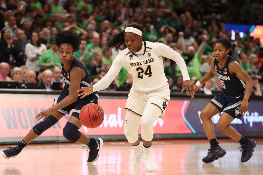 Arike Ogunbowale of the University of Notre Dame controls the ball in front of University of Connecticut players Christyn Williams and Crystal Dangerfield during the semifinals of the women's Final Four of the 2019 NCAA Tournament in Tampa, Florida.