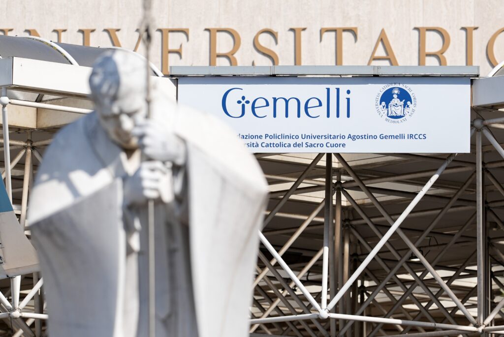 A statue of St. John Paul II is seen in front of the Gemelli hospital sign in Rome March 2, 2025. Pope Francis is receiving treatment there for double pneumonia. (CNS photo/Lola Gomez)