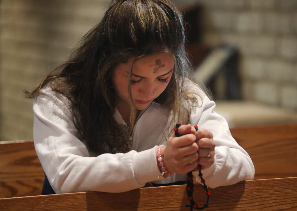 A young woman prays with a rosary following Ash Wednesday Mass at Sacred Heart Church in Prescott, Arizona, March 5, 2025.