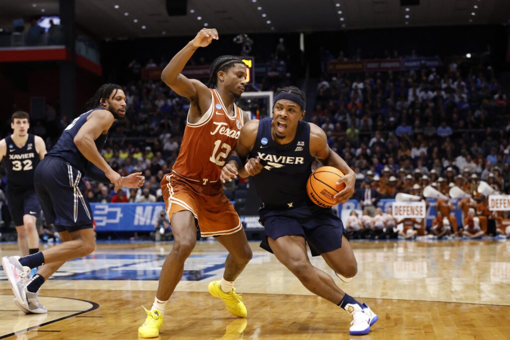 Xavier Musketeers guard Ryan Conwell (7) dribbles the ball defended by Texas Longhorns guard Tramon Mark (12) in the second half of a March 19, 2025, game during the NCAA's "First Four" elimination round at UD Arena in Dayton, Ohio. Xavier beat Texas 86-80.