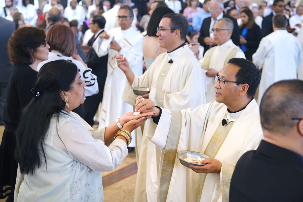 Auxiliary Bishops Felipe Pulido and Michael M. Pham (right) distribute Communion during their episcopal ordination Mass at St. Therese of Carmel Church in San Diego on September 28, 2023.