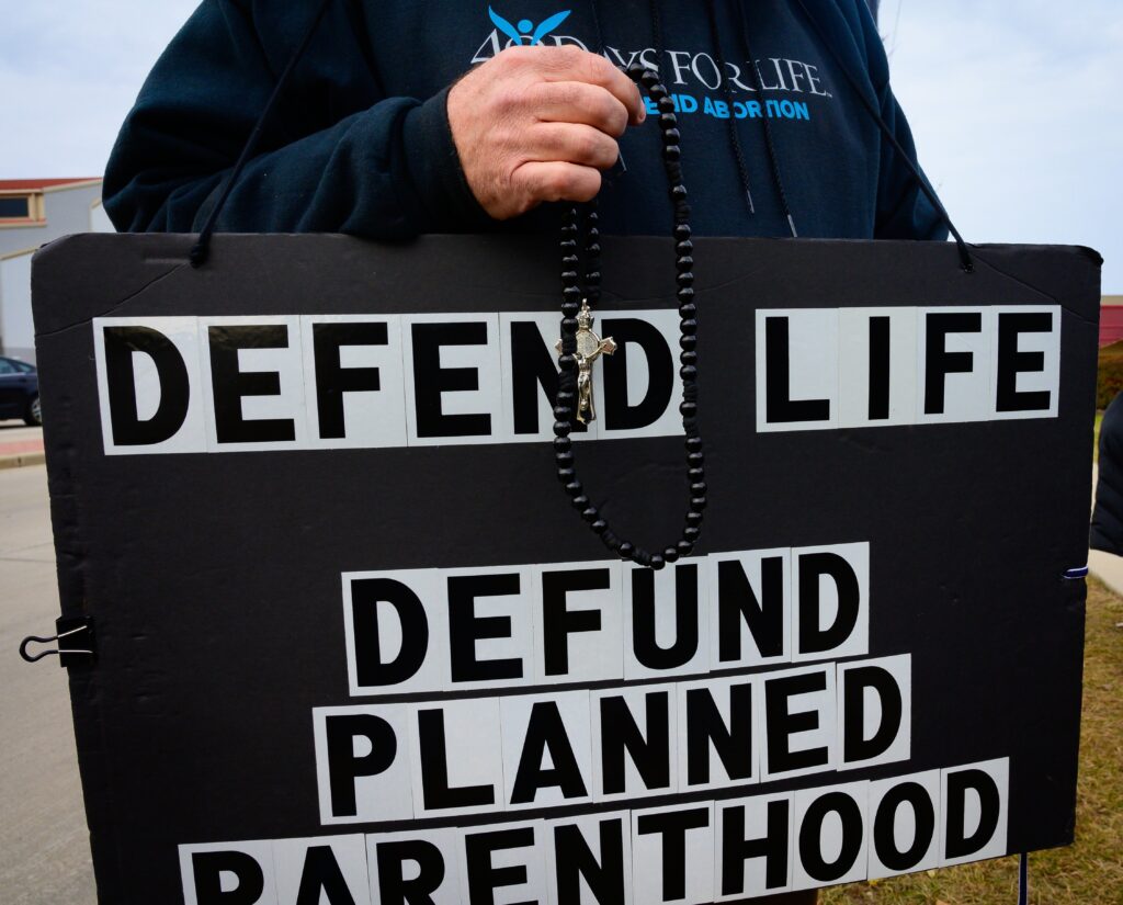 A pro-life advocate holds a rosary and sign in this file photo from November 3, 2019.