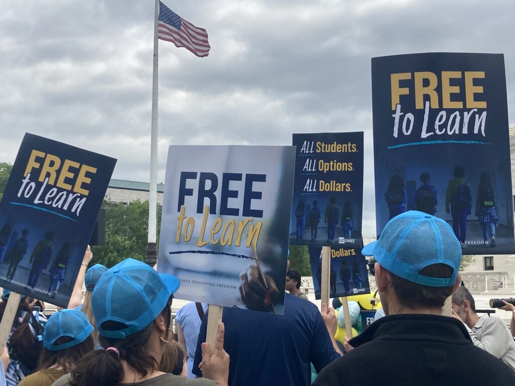 People hold signs in front of the U.S. Supreme Court in Washington on April 30, 2025, in support of a proposed Catholic charter school, St. Isidore of Seville Catholic Virtual School, in Oklahoma.