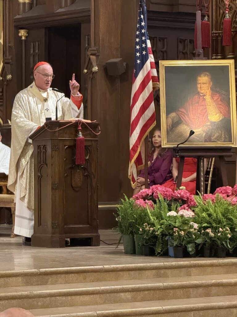 Cardinal Timothy Dolan appears with a portrait of his predecessor, Cardinal John McCloskey, the first American and first non-European cardinal, named in 1875.