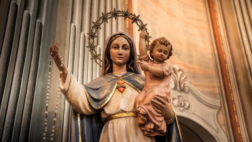La estatuilla representa al Inmaculado Corazón de María, que en sus brazos sostiene al niño Jesús.