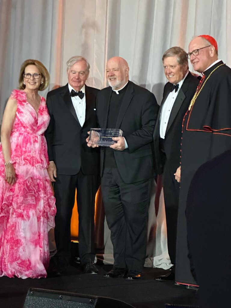 Monsignor Kevin Sullivan (center), executive director of Catholic Charities of New York, receives a lifetime achievement award named for him at the organization’s annual gala, held Wednesday, June 4, 2025, at the American Museum of Natural History in Manhattan.