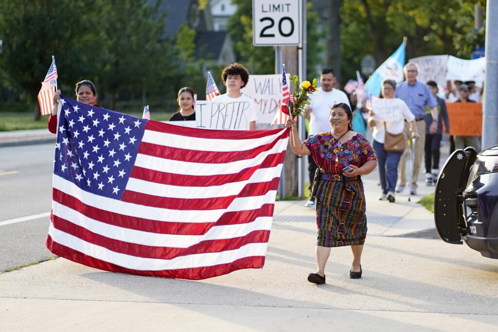 Women hold a U.S. flag as they lead a pro-immigrant march following a Spanish-language Mass at St. John the Evangelist Church in Riverhead, on June 22, 2025, the feast of the Body and Blood of Christ.