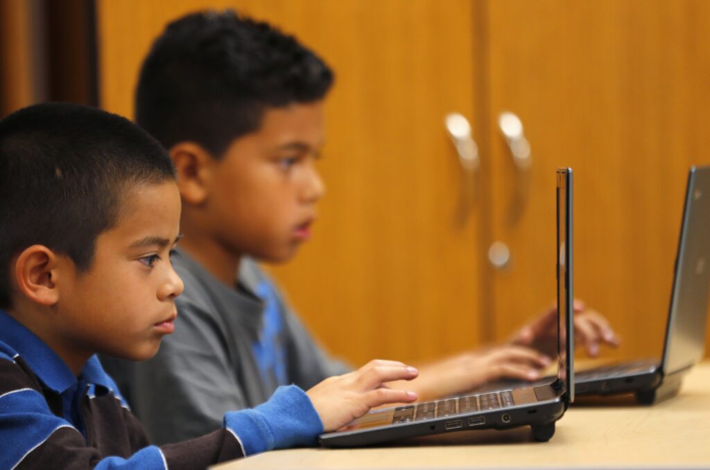 Fourth-grade students are pictured in a file photo working on laptop computers at Monarch School in San Diego.