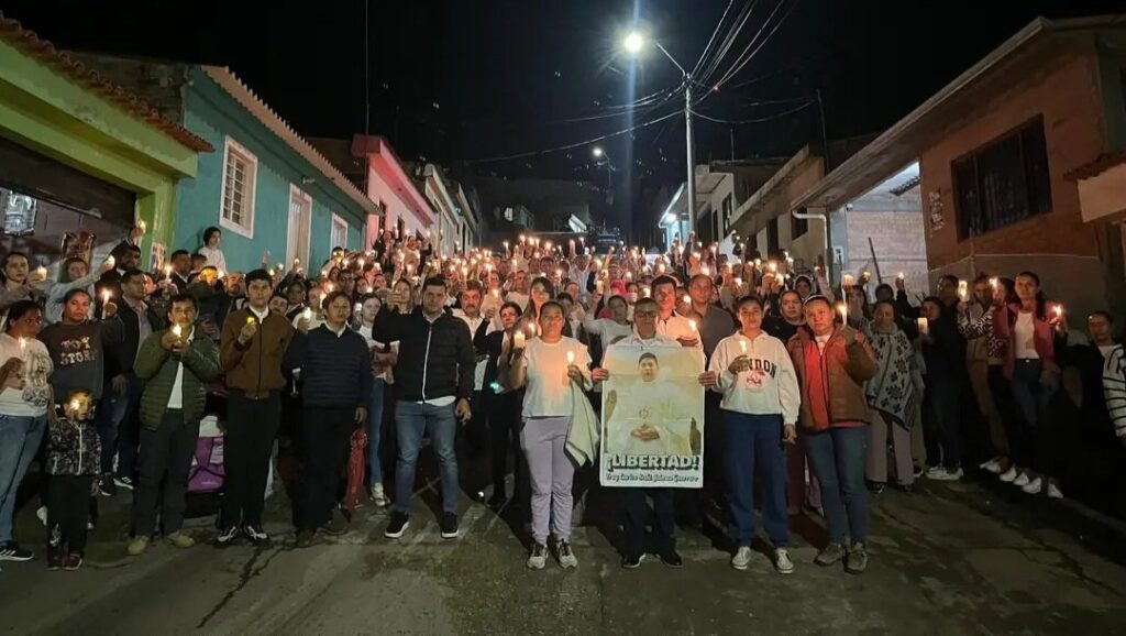 Manifestantes participan en una marcha nocturna en Viotá, Colombia, el 26 de junio de 2025. Cientos de residentes portan velas y pancartas con fotos del padre Carlos Jaimes Guerrero.