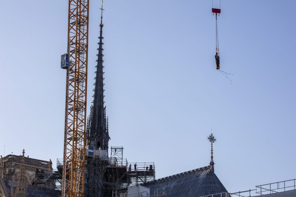A statue of St. Paul, the first of the 16 now-renovated statues that adorn the roof of Notre Dame Cathedral in Paris, is lifted by a crane June 23, 2025, marking the last phase of reconstruction of the cathedral's roof, damaged by the April 2019 fire.