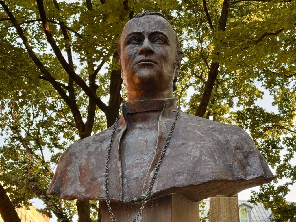 A statue of the first Archbishop of New York, John Hughes, stands in front of Old St. Patrick's Cathedral, photographed on July 15, 2025.