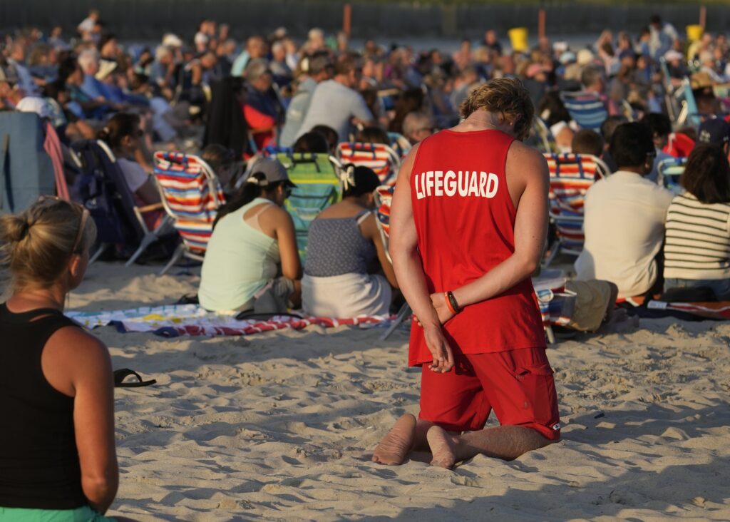 Lifeguard Brian Peknic bows his head in prayer as he attends the weekly summer Sunday evening beach Mass in Long Beach, July 20, 2025.