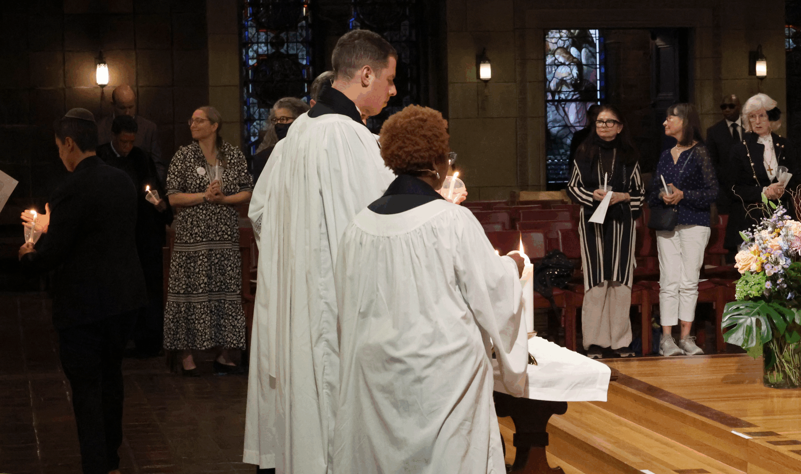 Faith leaders from St. Bartholomew’s Church light candles to join the congregation in a candlelit vigil to remember the lives lost.