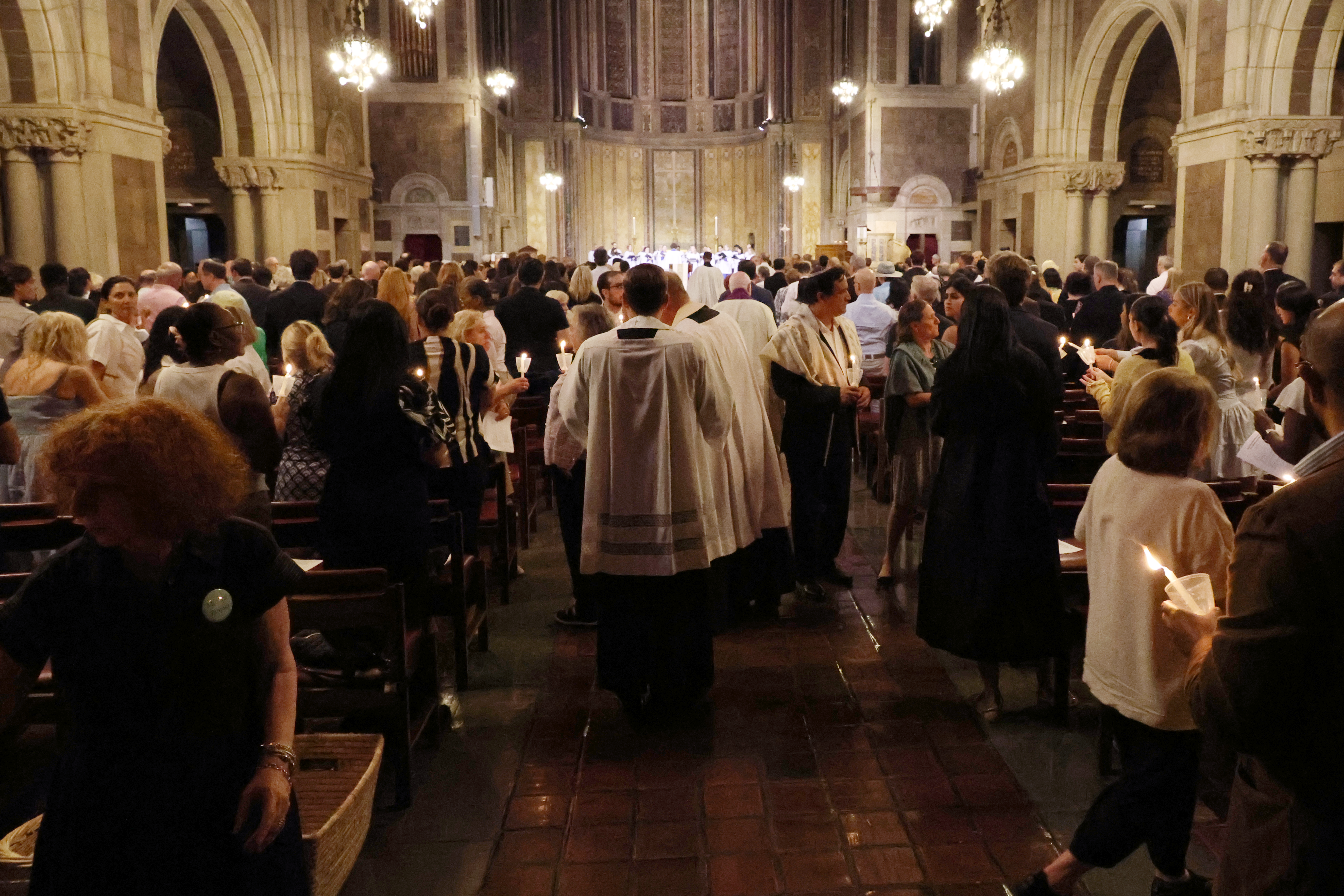 Interfaith leaders join the crowd to light the candles of those in attendance.