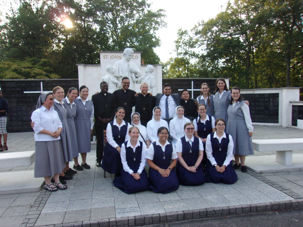 The five young men who professed vows on Friday, August 15, pose with Salesian Sisters of St. John Bosco at the Mary, Help of Christians Shrine in Stony Point.